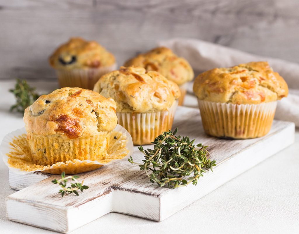 Chicken, cheese and olives muffins on light grey background. Savory muffins. Healthy lunch or snack.