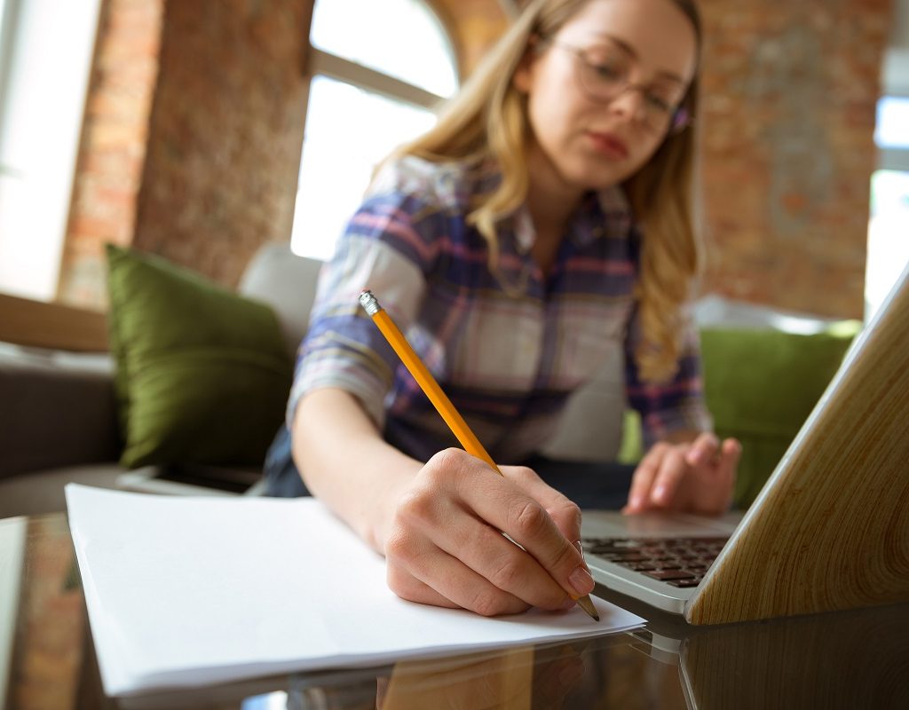 Young woman studying at home during online courses or free information by herself. Becomes musician, violinist while isolated, quarantine against coronavirus spreading. Using laptop, smartphone, headphones.