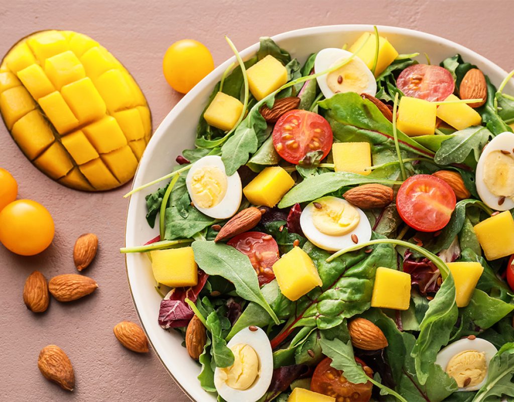 Plate of fresh mango salad on color background