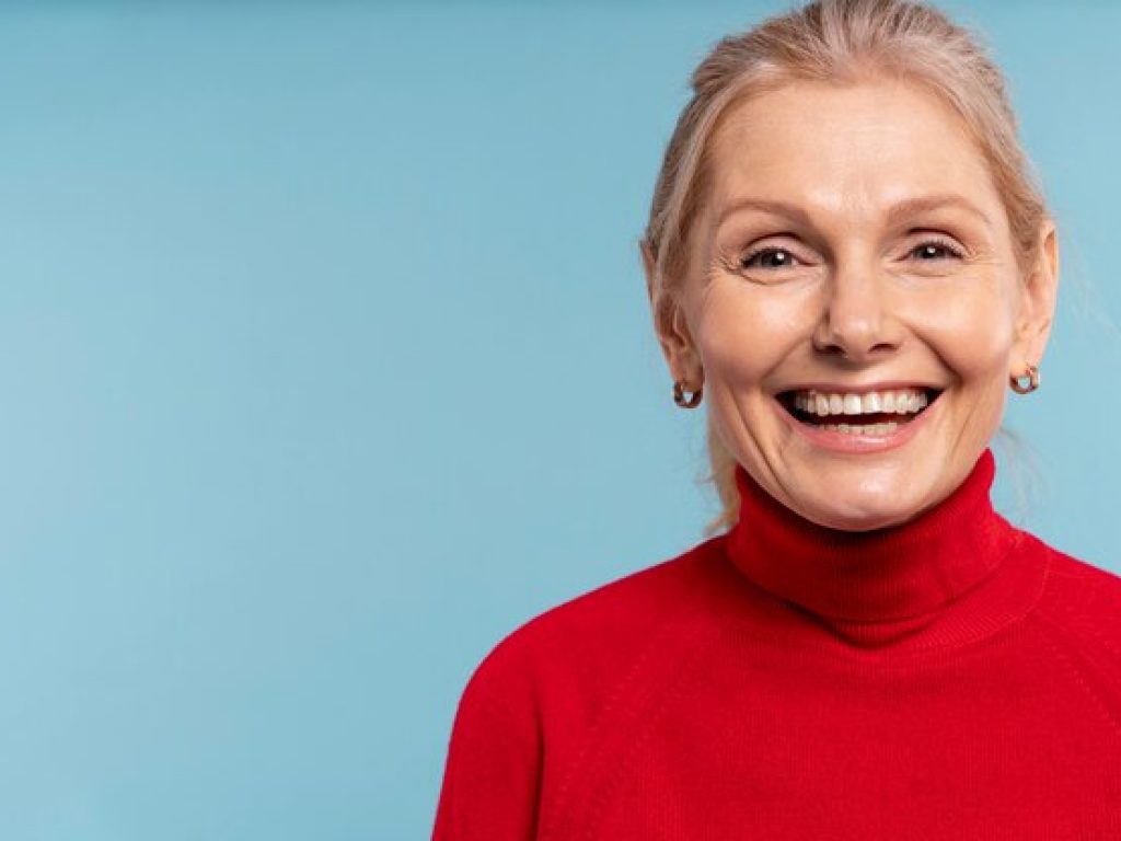 mulher-loira-senior-sendo-feliz-e-sorrindo-contra-um-fundo-azul