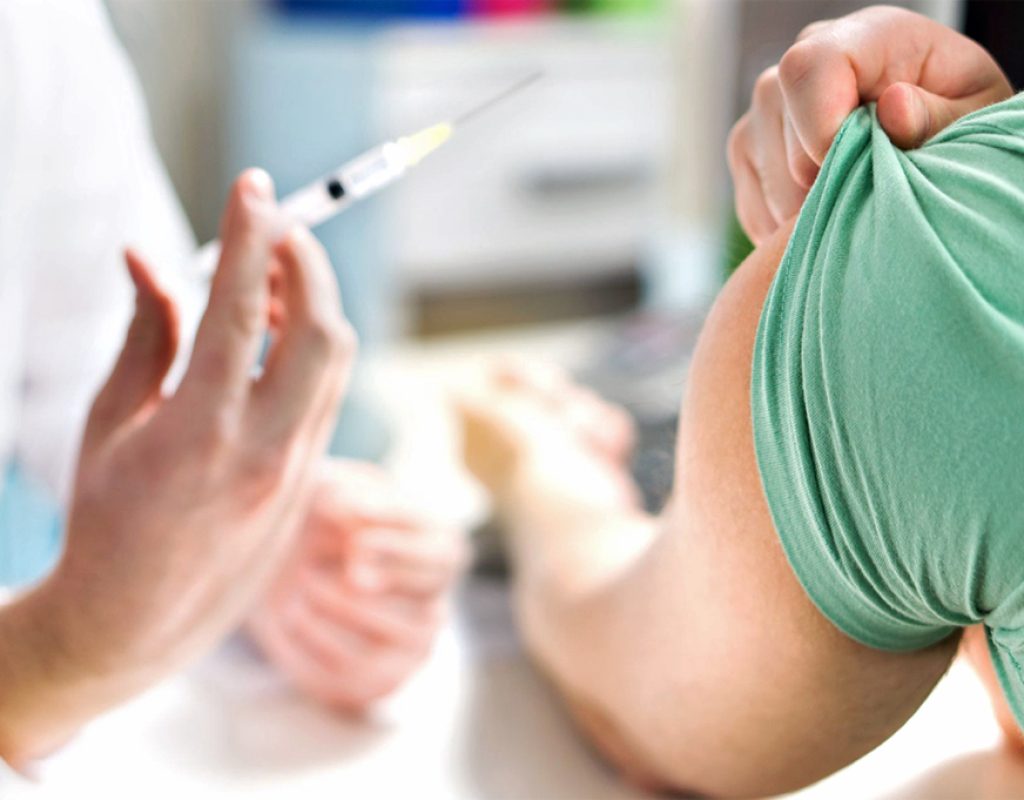 Doctor giving patient vaccine, flu or influenza shot or taking blood test with needle. Nurse with injection or syringe. Medicine, insulin or vaccination. Hospital office room.