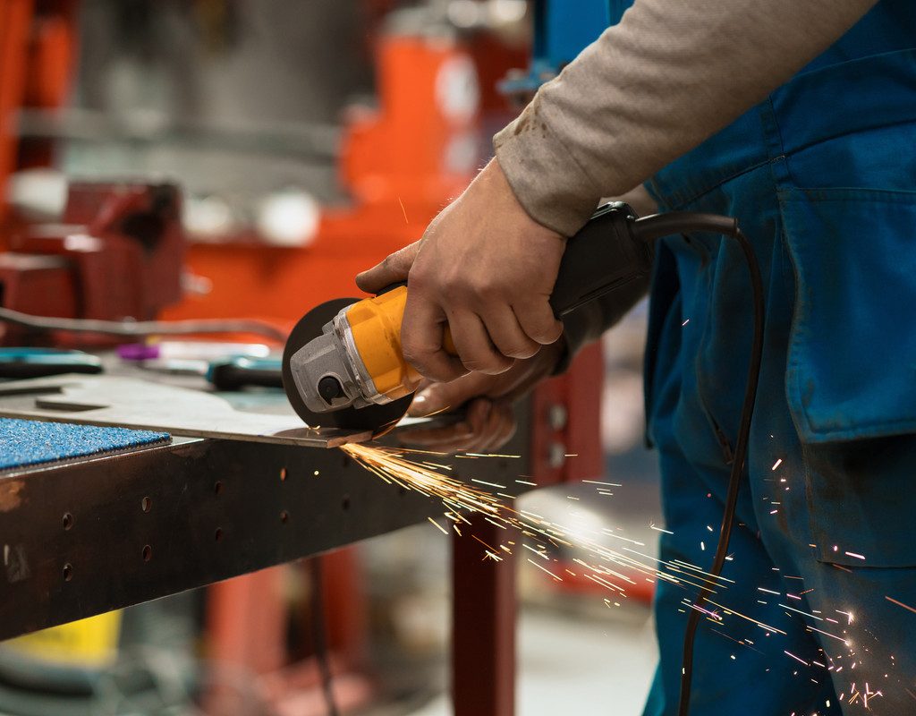 Technician worker cutting metal with many sharp sparks. Using equipments to cat iron